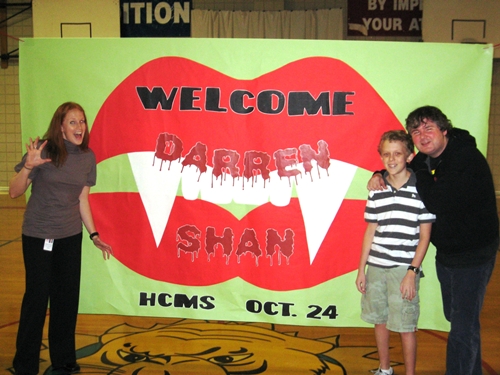 Shan poses in front of a welcome banner at Hill Country Middle School in Austin